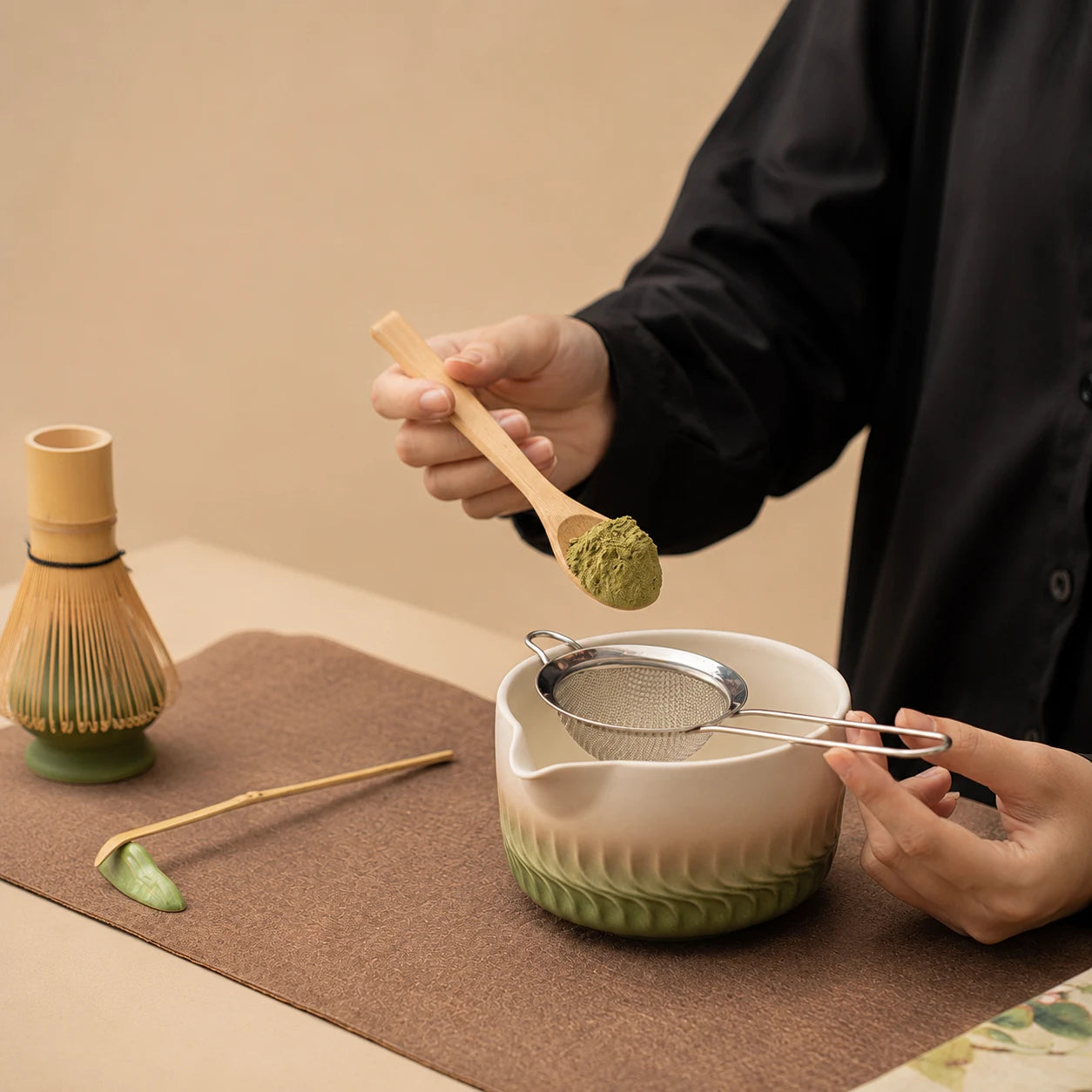Dosage du matcha au-dessus du bol Genpu vert dégradé avec tamis