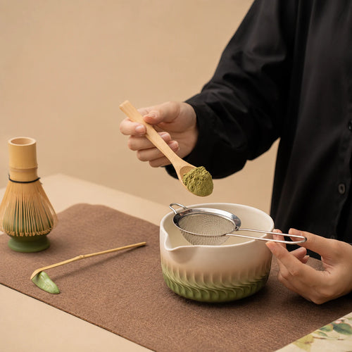 Dosage du matcha au-dessus du bol Genpu vert dégradé avec tamis