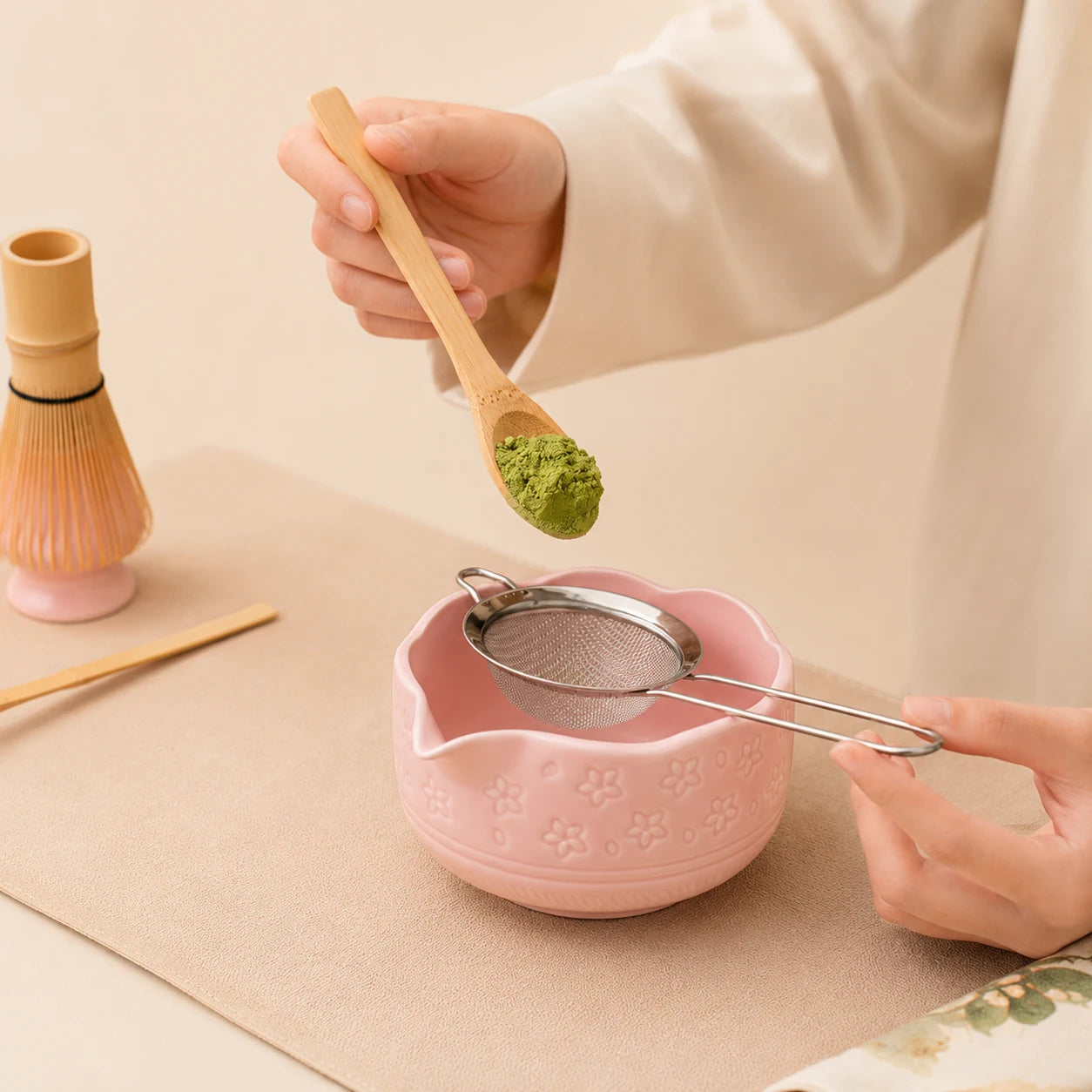 Dosage du matcha au-dessus du bol Komorebi rose uni avec tamis